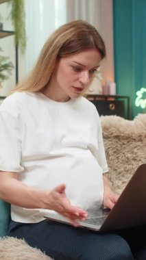 Hamile, orta yaşlı bir kadın dizüstü bilgisayarın donduğunu, el dalgalarının bozulduğunu ve cihazın gürültülü bir şekilde bozulduğunu görüyor. Kanepede oturan beyaz kız bebek vaktinden önce teknolojik hatalarla boğuşuyor..