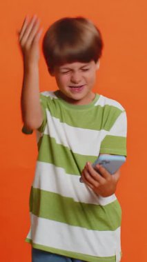 Üzgün çocukluk çağındaki çocuk akıllı telefon daktilo kullanıyor, oyun oynuyor, kaybediyor. Ani piyango sonuçlarına şaşırıyor. Kötü talih, kayıp, başarısızlık, şanssız haber. Kapalı alanda turuncu arka planda üzgün çocuklar