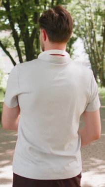 Sportif genç erkek sporcu parktaki yaya yolunda kameraya gülümsüyor. Kollarını kavuşturarak koşan kendine güvenen erkek koşucunun portresi. Spor sağlık, spor rutini, egzersiz. Kuvvet ve motivasyon.