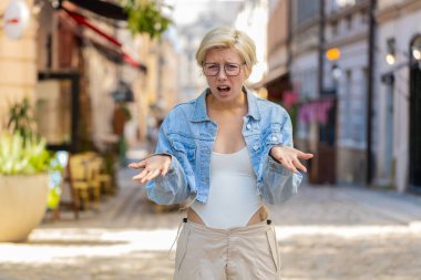 Hayal kırıklığına uğramış, omuz silken, üzgün, genç, sarışın bir kadın. Cevap vermiyor. Tepkisi belirsiz..