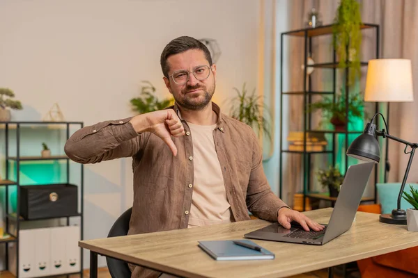 Hoşlanmamak. Mutsuz bir adam dizüstü bilgisayar kullanıyor ve işaret dilini gösteriyor. Memnuniyetsizliğini dile getiriyor. İç işlerindeki kötü işleri tasvip etmiyor. Masadaki serbest çalışan genç adam memnun değil..