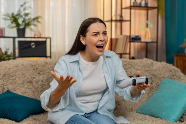 Heyecanlı genç bir kadın kanepesinde oturup oyun oynarken heyecan verici oyun oyunlarına duygusal tepkiler veriyor. Kafkasyalı kız eğlence zamanı, dışavurum, oyuncu duyguları...