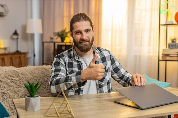 Mutlu gülümseyen genç adam ev masasındaki görevlerini tamamlıyor, bilgisayarını minnettar bir ifadeyle kapatıyor. Kanepede oturan beyaz bir adam kameraya doğru dönüyor, iyi bir iş çıkardığını söylüyor..