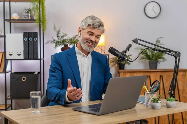 Merkez ofisteki orta yaşlı işadamı canlı jestler kullanarak podcast 'i stüdyo mikrofonuna aktarıyor. Masadaki serbest çalışan adam soruları cevaplıyor. Ses tonunu neşeli dinleyiciler canlı tutuyor..