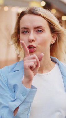 Sessiz olun lütfen. Sarışın genç bir kadın işaret parmağını dudaklarına bastırıyor. Sessiz ol işareti yapıyor. Dışarıdaki dedikoduları kimseye söyleme. Genç bayan şehir caddesinde duruyor. Kasaba yaşam tarzları