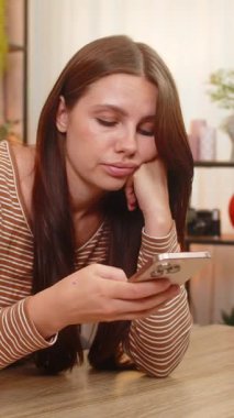 Evdeki genç kadın akıllı telefondan haber yolluyor. Sıkılmış görünüyor ve sürekli gönderilerden yorgun düşüyor. Masadaki beyaz kız mutsuz görünüyor. Görevleri ihmal ediyor. İç çekiyor, duygusal çöküntü yaşıyor ve kendini kötü hissediyor.