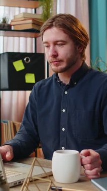 Kafkasyalı genç işadamı dizüstü bilgisayarda çalışıyor sıcak kahve içiyor ve sabahları çalışma odasındaki masada oturuyor. Serbest çalışan erkek. Rahatlıyor, dinleniyor..