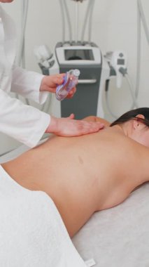 Terapistin yağ sürmesi ve kadının spa 'yı gevşetmesi sırt masajını pürüzsüz el hareketleriyle canlandırması. Zayıflatıcı vücut şekillendirme. Fiziksel Güzellik Uzmanı Kozmetik Seansı müşterisi