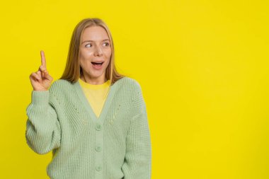 - İyi fikir. İlham verici orta yaşlı bir kadın, parmağını açık ağızla işaret ederek plan yapıyor, girişimde bulunuyor, Eureka jest sorunu çözümü için ilham kaynağı gösteriyor. Sarı arka planda izole edilmiş yetişkin bir kız.