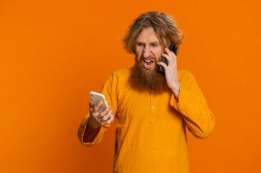 Sinirleri bozuk, iki cep telefonuyla bağıran, gergin, beyaz bir adam. Tartışma, tartışma, anlaşmazlık, sorun çözme tartışması yapıyor. Genç adam turuncu arka planda izole