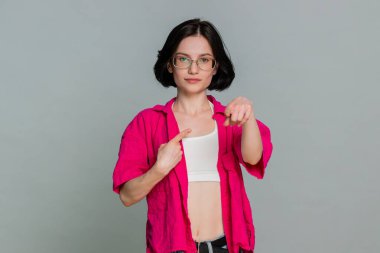 Genç bir kadın önce kendine güvenir sonra da doğrudan kameraya bakar. Bu da seni seçtiğimi gösterir. Beyaz kız, gri arka planda kendine güvenen bir seçim ve dostça bir davet sundu.