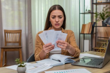 Masadaki genç kadın faturaları okuyor ve kaşları çatıyor. Sonra da kağıtları masaya fırlatıyor. Beyaz kız iflastan ve artan maliyetlerden korktuğu için afalladı..