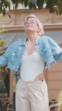 Gözlüklü sarışın kadın derin bir nefes alıyor, dinleniyor, dinleniyor, meditasyon yapıyor, sakinleşiyor. Şehir caddesinde mutlu bir gün geçiren bir kız. Kasaba yaşam tarzları.