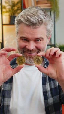 Gülümseyen Kafkasyalı kıdemli serbest çalışan hisse senedi tüccarı altın bitcoin BTC ile gözlerini kapatıyor. Mutlu orta yaşlı erkek arkadaş başarılı geliştirici programcı sınıftaki kanepede. Zenginlik artıyor