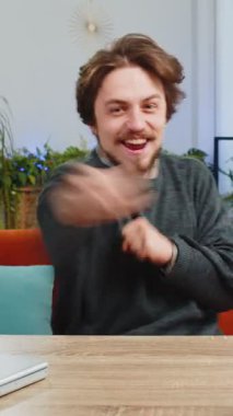 Mutlu Kafkas adam bağırıyor, başarıyı kutluyor, kazanıyor, gol başarısı iyi haber piyango zaferi, modern ev dairesinde TV şampiyonluğu izliyor. Ofisteki sakallı adam masada oturuyor.