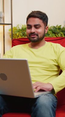 Hintli bir adam dizüstü bilgisayara bakıyor, arkadaşları ya da ailesiyle görüntülü bir konferans görüşmesi yapıyor, modern apartman dairesinde hoş sohbetler ediyor. Arap adam gülüyor, el sallıyor ve sandalyede oturuyor.