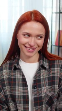 Genç bir kadın kameraya göz kırpıyor. Cilveli bir gülümsemeyle kendine güveni ve cazibesini gösteriyor. Kafkasyalı kızıl saçlı kız kanepenin üzerinde eğleniyor, duygularını ve kişisel çekiciliğini ifade ediyor.