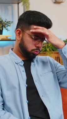 Hasta Hintli adam baş ağrısı problemini tedavi etmek için tapınakları ovuyor, tansiyon, migren, stres, ekşitme, evde yüksek tansiyon. Arap adam evdeki kanepede gözlük çıkartıyor..