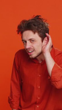 - Seni duyamıyorum. - Ne? Kafkasyalı bir adam senin şaşırmış ve kaşlarını çatmış bir şekilde daha yüksek sesle tekrar etmek, bilgi almak ve sağır olmak için kolunu kulağının dibinde tutmaya çalışıyor. Turuncu arka plandaki genç adam.