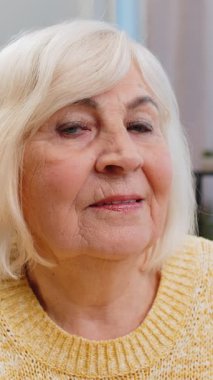 Mutlu yaşlı bir kadının yakın plan portresi mutlu mutlu bir surat ifadesinin dinlenme hayalleri tatmin edici bir konsept iyi haberler evde zaferi kutlar. Yaşlı olgun büyükanne masada oturuyor.