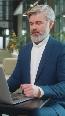 Takım elbiseli kızgın yetişkin patron, ofiste modern işyerinde otururken bilgisayarla video görüşmesi yapıyor. Tatminsiz iş adamı yöneticileri, şirketlerin sorunları hakkında astlarıyla iletişim kuruyor..