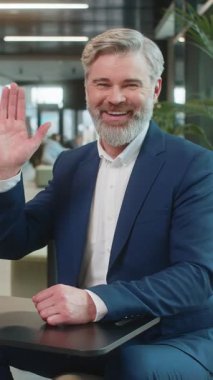 Hoş geldiniz. Kafkas 'lı mutlu iş adamı el sallayarak selam veriyor. Birine hoş geldin diyor. İnternetteki Webinar, uzaktan konuşma. Takım elbiseli girişimci adam modern ofis lobisinde oturuyor..