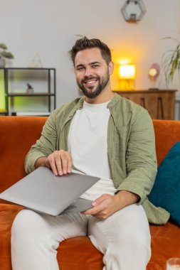 Kahverengi saçlı, beyaz bir adam oturma odasındaki işi bittikten sonra bilgisayarını kapatıyor. Mutlu genç adam serbest çalışıyor. Evinde uzaktan kumanda işinde çalışıyor. Bilgisayarda E-öğrenme, internette gezinme