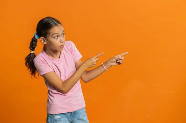 Ergenlik çağındaki kız çocuğu boş bir yeri işaret ediyor. Ticari indirimli mesajlar için reklam alanı, ürün tanıtımı için fotokopi alanı. Turuncu arka planda ergen çocuklar