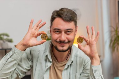 Serbest çalışan genç bir borsa simsarı sanal paraların BTC tarafından izlendiğini gösteriyor. Zenginliğin finansal refahı artıyor. Ofis masasında dizüstü bilgisayarı olan adam..