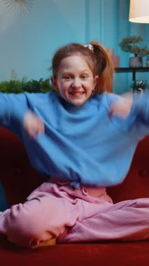 Mutlu kız bağırıyor, başarıyı kutluyor, kazanıyor, gol başarısı, iyi haber, piyango şansı, zafer, modern ev dairesinde televizyon şampiyonluğu seyrediyor. Gece odasında kanepede oturan genç bir çocuk.