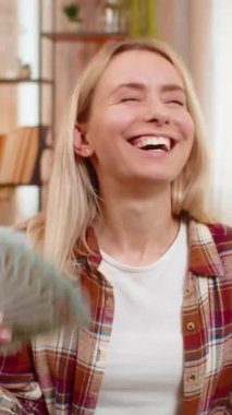 Genç, yetişkin bir kadın bir tomar banknotla el ele tutuşup koltukta oturuyor ve büyük bir sevinç yaşıyor. Sarışın kız büyük finansal zaferini kutluyor. Gülümsüyor ve zaferin duygusal anının tadını çıkarıyor.