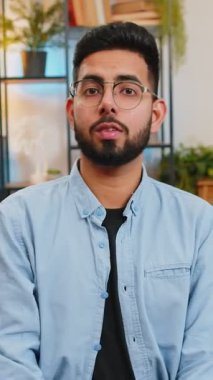 Hey sen! Mutlu Hintli adam gülümsüyor ve kamerayı işaret ediyor, şanslı kazananı seçiyor, muhteşem olduğunu gösteriyor, davet ediyor, onaylıyor, seçiyor. Oturma odasındaki Arap adam kanepede oturuyor..