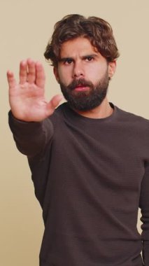 Hintli bir adam, el hareketini durdurma, bitirme uyarısı, erişimi yasaklama, iletişimi kesme, vücut dili, tehlike. Bej arka planda Latin Hintli genç bir adam. İnsan yaşam tarzları.