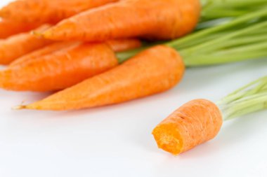 Beyaz tabakta yaprağı olan havuçlar.