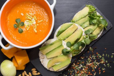 Kabak ve havuç çorbası, kızarmış pirinç kraker avokado kara tahta arka plan ile yuvarlak kremi.