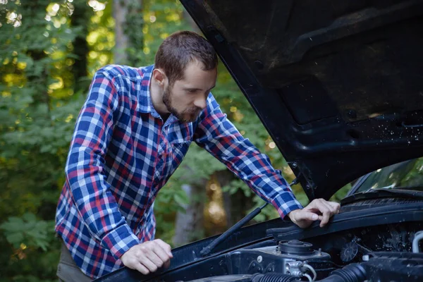 El tipo mira el motor del coche. — Foto de Stock