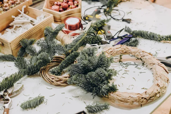 Creating a Christmas wreath of spruce branches and a cardboard frame. Craft paper. Decoration for the house for Christmas. Concept of florist\'s work before christmas holidays.