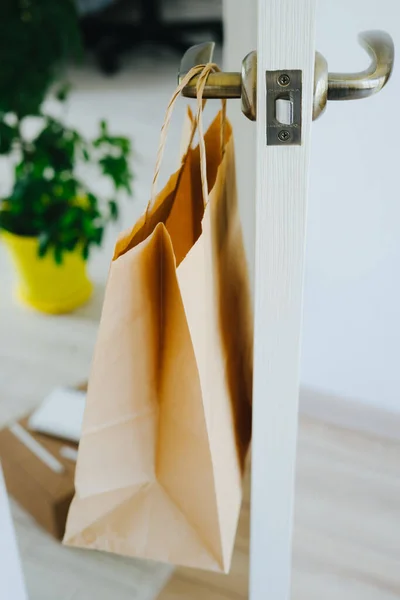 The craft package hangs on the handle from the front door. The package with products is delivered by courier contactless. Shopping online. Delivery to the door.