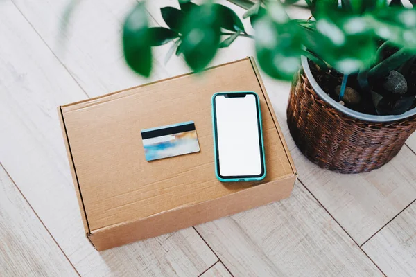 Making purchases online. Sale. Online shopping. Box, a smartphone and a plastic credit card to pay for the goods received. Delivery by courier to the door. Buy sitting at home.