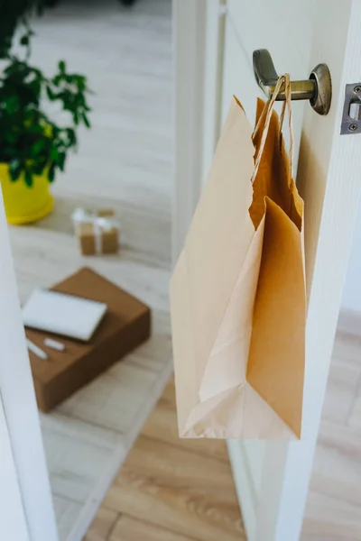 The craft package hangs on the handle from the front door. The package with products is delivered by courier contactless. Shopping online. Delivery to the door. Buy sitting at home.