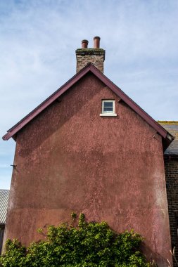 Mavi ve beyaz gökyüzü arka planına karşı kırmızı bir ev. 
