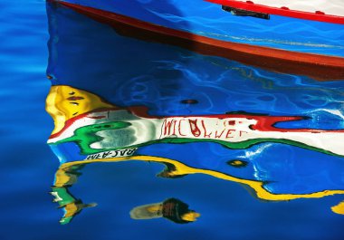 Marsaxlokk, Malta-jul 12: Marsaxlokk köyünde bir su üzerinde renkli balıkçı teknesi yansıması, Malta.Bir su üzerinde geleneksel Malta balıkçı teknesi yansıması soyut görünümü. Renkli arka plan