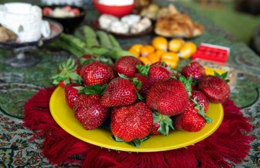 Diğer Malta aperatifleriyle birlikte sarı tabakta servis edilen taze çilekler. Bulanık arkaplan