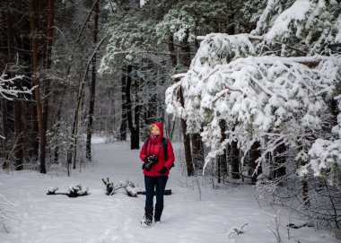 Beyaz, beyaz, kırmızı ceketli bir kadın. Karlı bir günde beyaz orman geçmişiyle eğleniyor. Noel zamanı. Mutluluk. Kar yağışıweather condition