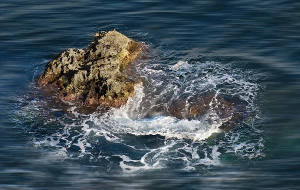 Ocean background. Little rock in the middle of the sea. Rock isolated in blurry motion sea background. Nature background. Nice blue sea