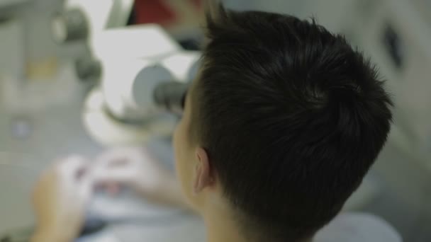 Dental technician looks into the microscope — Stock Video