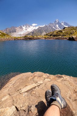Chamonix-Mont-Blanc 'taki Alp Vadisi' nde göle bakan yürüyüş botları giyen adam Fransa 'nın güneydoğusunda Auvergne-Rhone-Alpes bölgesinde Haute-Savoie bölümünde komün.