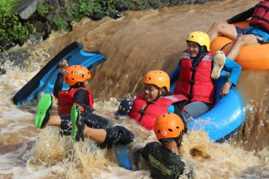 Neşeli bir atmosfer ve güneşli hava ile, Pandansari nehri üzerinde şamandıralar ile bir nehir akışı yaparken Turistler
