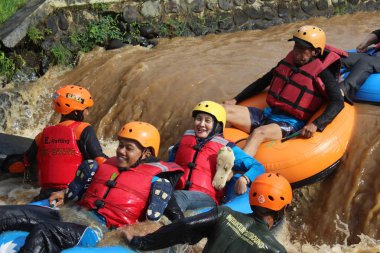 Neşeli bir atmosfer ve güneşli hava ile, Pandansari nehri üzerinde şamandıralar ile bir nehir akışı yaparken Turistler