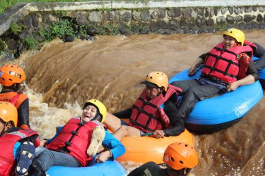 Neşeli bir atmosfer ve güneşli hava ile, Pandansari nehri üzerinde şamandıralar ile bir nehir akışı yaparken Turistler